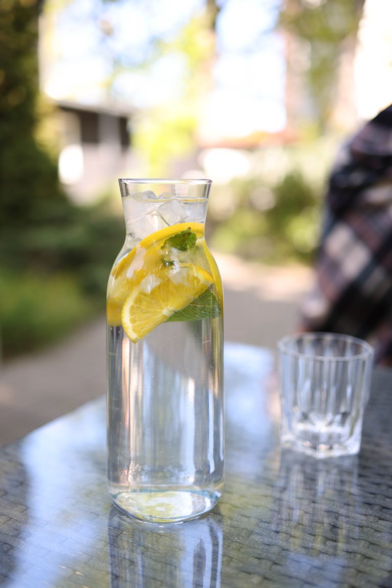 Citrus mint and water in a glass carafe in the sun making a sun tea solar infusion