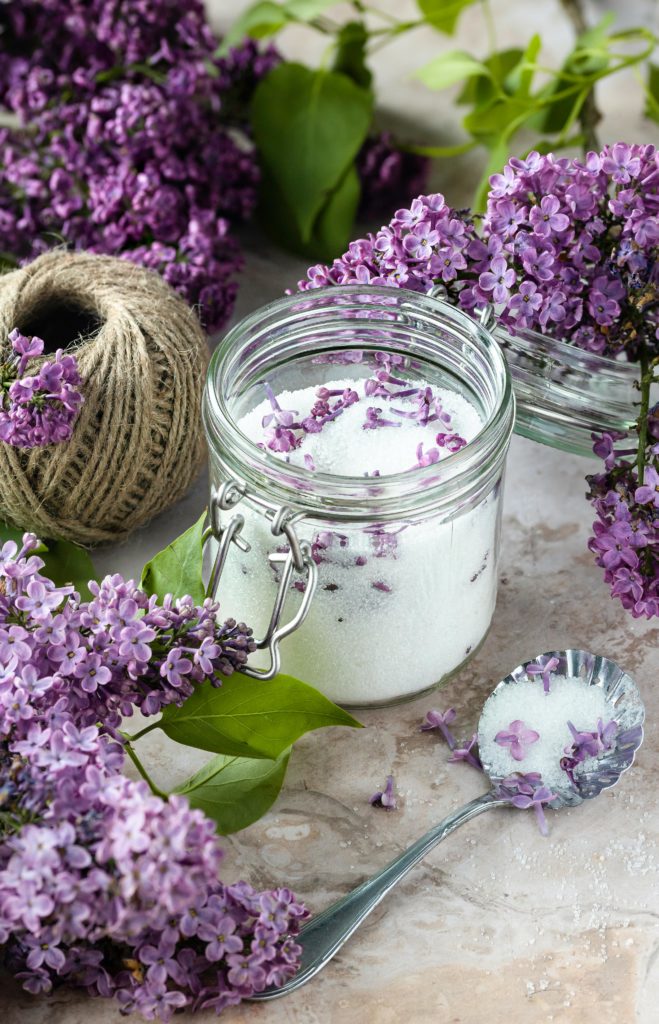 A mason jar filled with aromatic lilac-infused sugar, adorned with fresh lilac blossoms, capturing the essence of spring in a delightful culinary creation